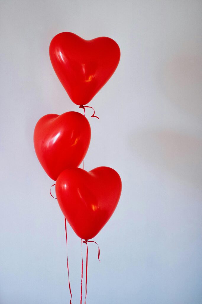 pexels-photo-704748-704748 Three red heart-shaped balloons floating in a minimalist studio setting, evoking love and romance.