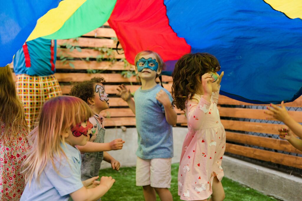 pexels-photo-8385872-8385872 Children with face paint enjoying an outdoor party with vibrant colors and playful activities.